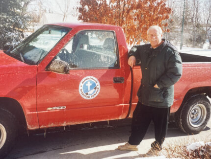 An MDS volunteer stands next to a red company truck.
