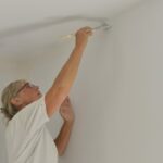 A woman touches up a wall with a paint brush