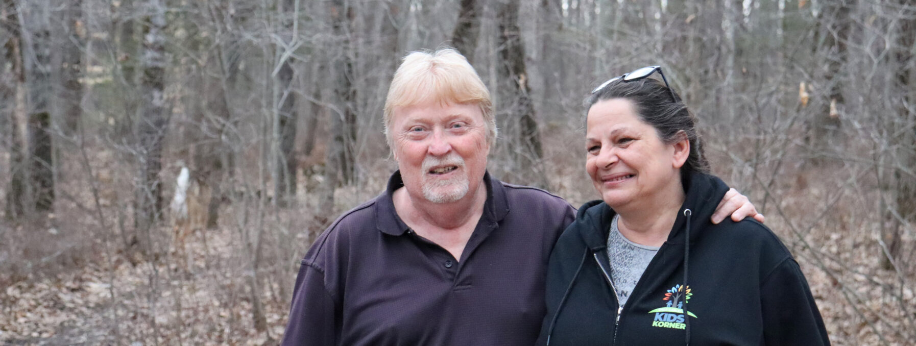 A candid shot of a couple in their wooded backyard.