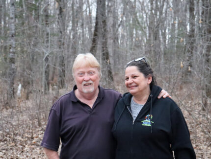 A candid shot of a couple in their wooded backyard.