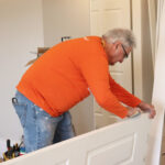 A man sands a door's edge