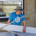 A volunteer prepares to install siding on a house