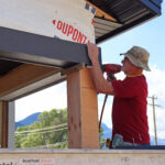 A volunteer helps build a house for wildfire survivors