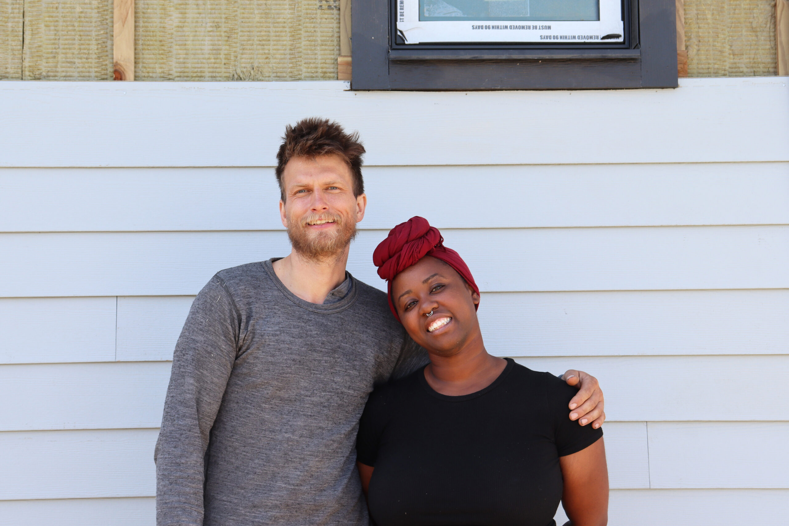 A couple stands next to a house under construction