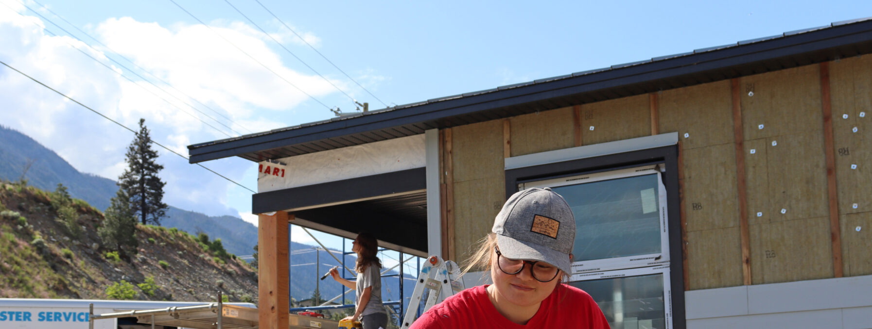 A woman paints siding