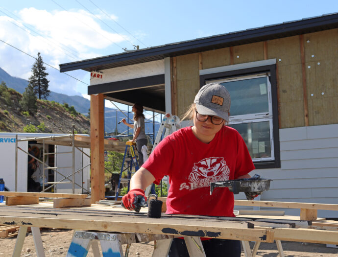 A woman paints siding