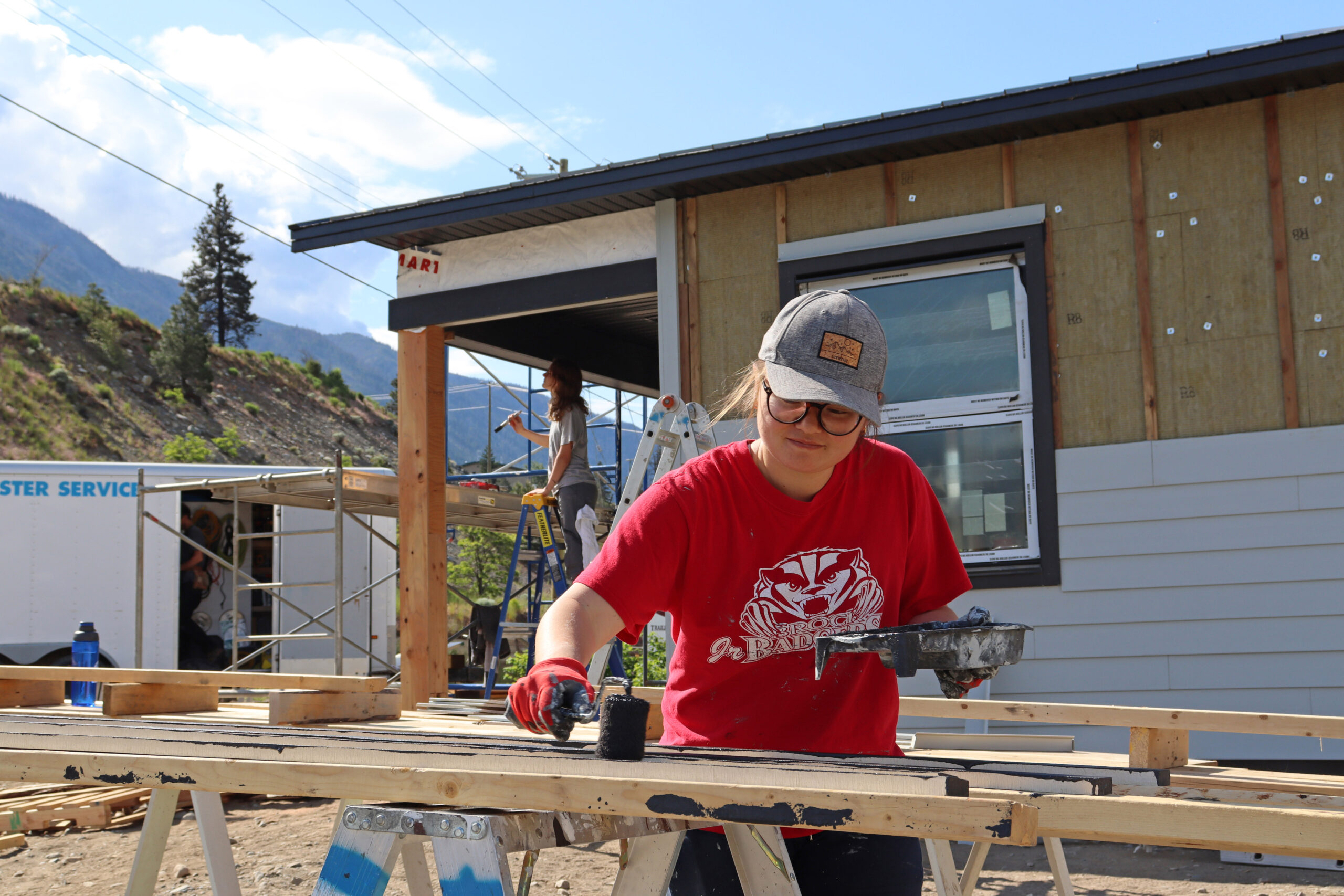 A woman paints siding