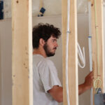 A volunteer prepares measurement for a bath installation in house construction