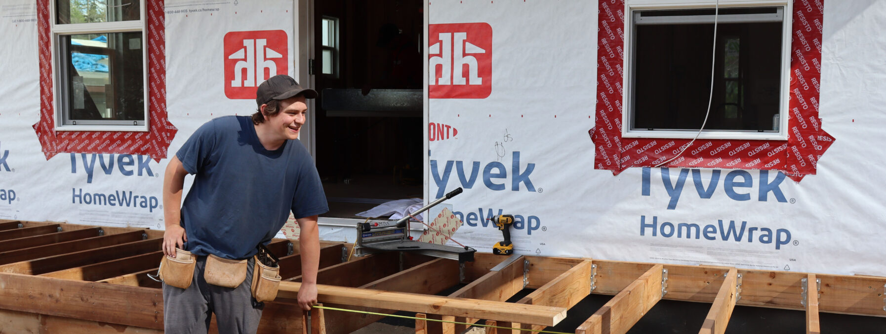 A young man measures a deck.