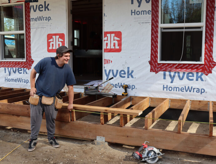 A young man measures a deck.