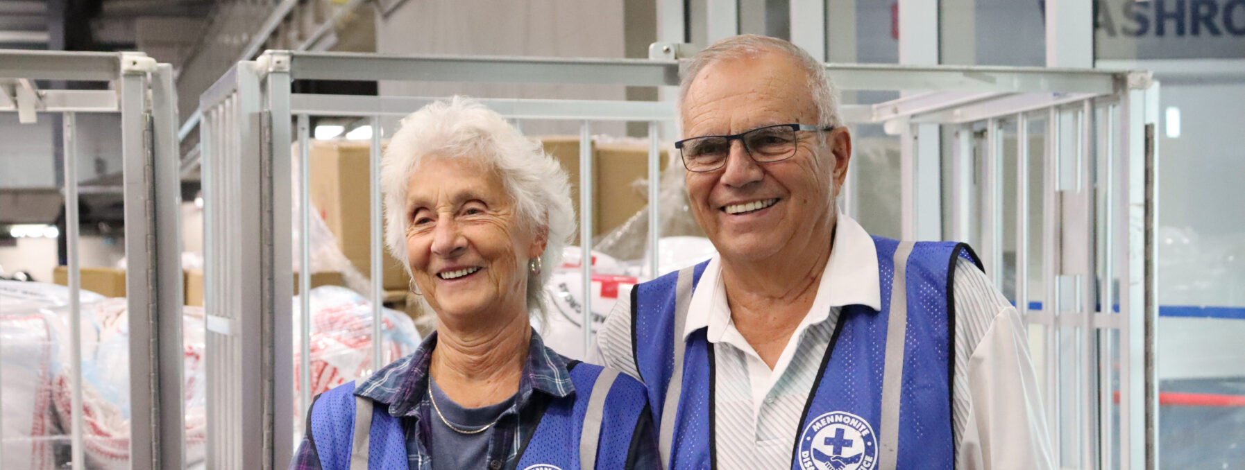 A woman and man in volunteer vests at a wildfire evacuee reception centre.