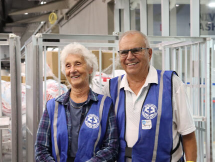 A woman and man in volunteer vests at a wildfire evacuee reception centre.