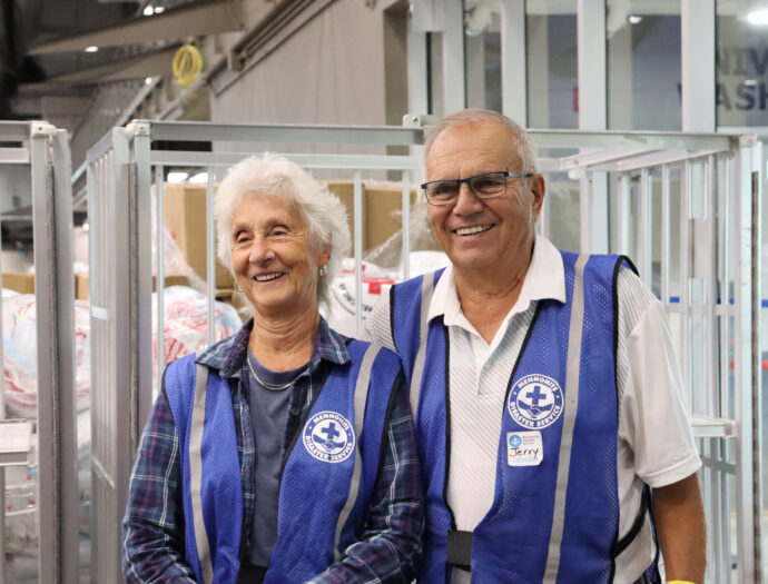 A woman and man in volunteer vests at a wildfire evacuee reception centre.