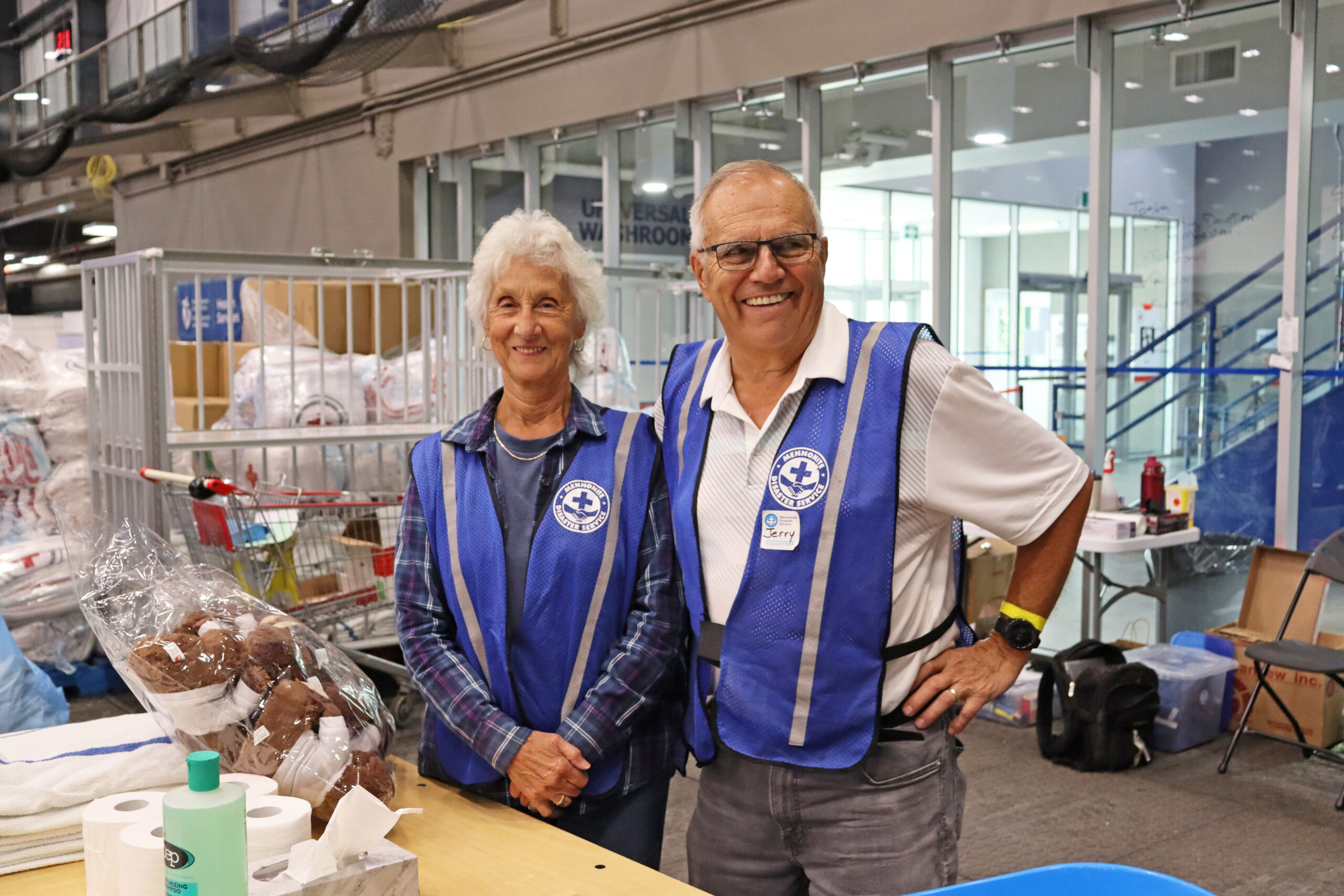 A woman and man in volunteer vests at a wildfire evacuee reception centre.