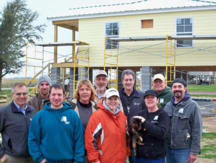 Group photo of MDS standing in front of elevated new build.