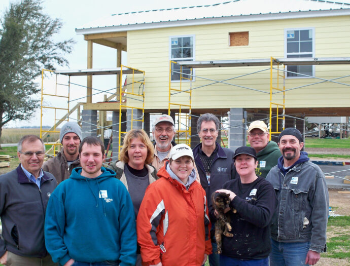 Group photo of MDS standing in front of elevated new build.