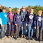 Group of 9 people standing together, posing for picture.