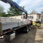 Flatbed truck delivering drywall to construction site.