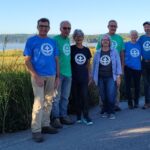 Group of volunteers standing infront of a lake.