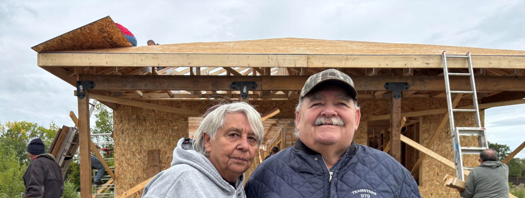 Man and woman stand in front of house that is under construction.