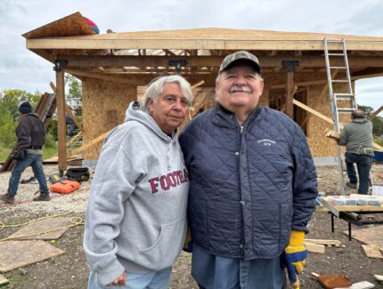Man and woman stand in front of house that is under construction.
