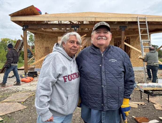 Man and woman stand in front of house that is under construction.