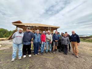 Group of people stand in front of house that is under construction.
