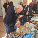 People serving themselves at a table of food and drinks.