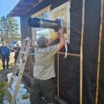 Man fixing ducting outside of a house.