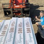 Man guides truck along as flooring is being unloaded.
