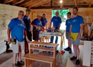 Group of people stand around a desk that they are constructing.