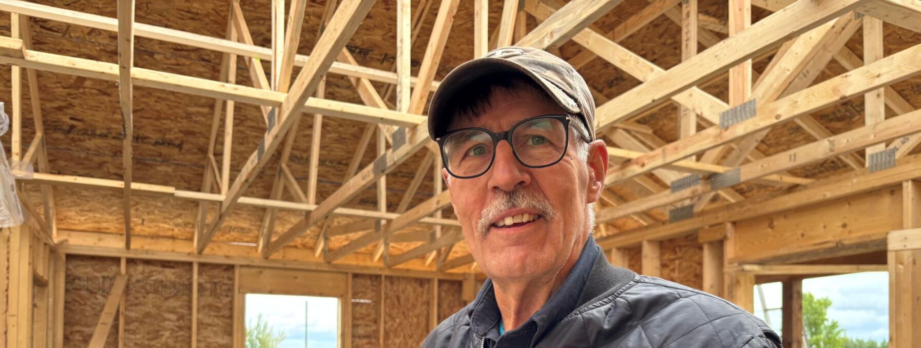 Man poses for picture insude a house build under contruction.