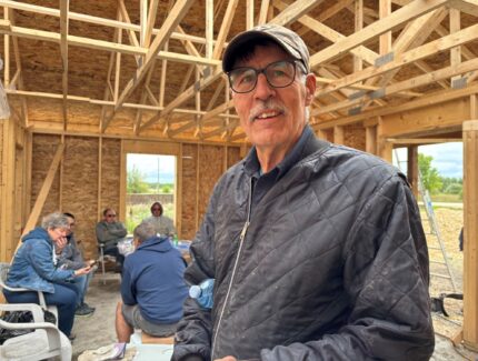 Man poses for picture insude a house build under contruction.
