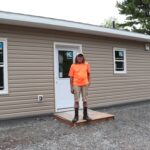 Man stands in front of house.