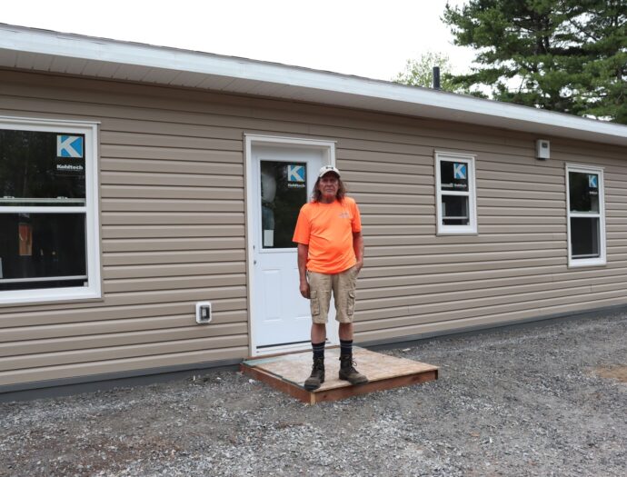 Man stands in front of house.