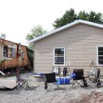 A mobile trailer on the left and a new house on the right.