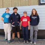 Four people stand in front of building under contruction.
