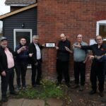 Group standing in front of a house, showing the house number.