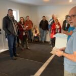 Group of people standing in a circle inside a home.