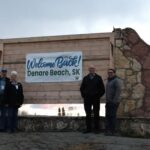 4 people standing in front of a town sign.
