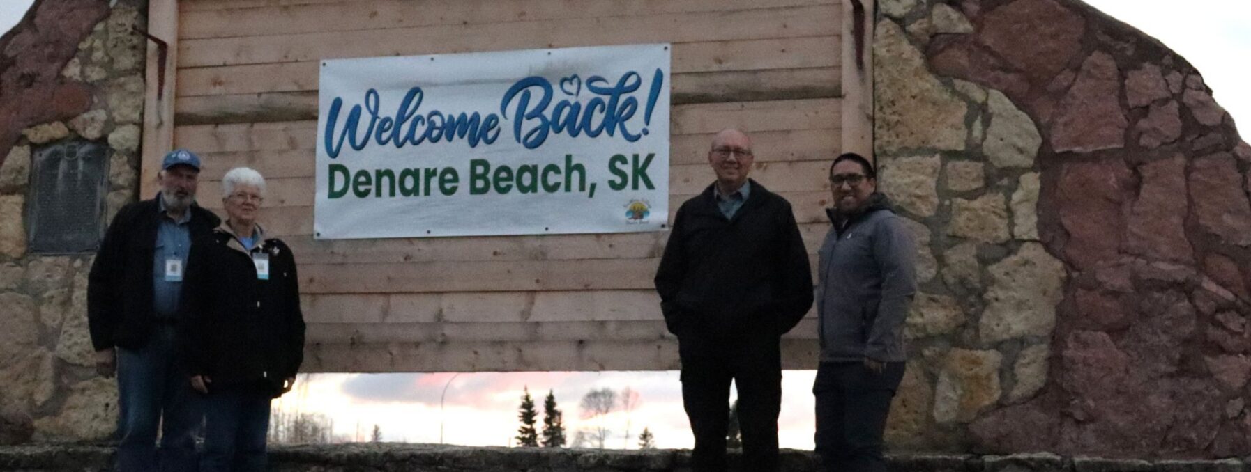 4 people standing in front of a town sign.