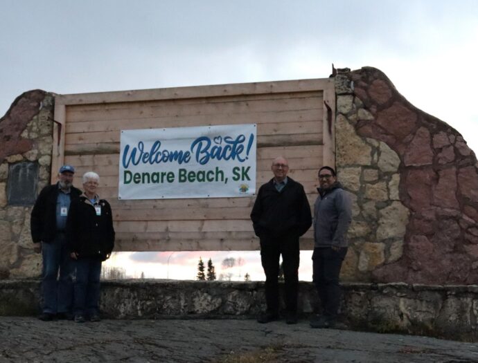 4 people standing in front of a town sign.