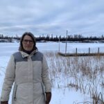 Woman standing in front of a frozen lake.