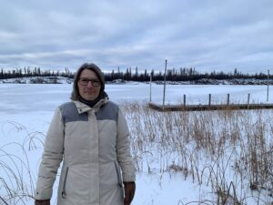Woman standing in front of a frozen lake.