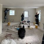 People dispersed in an open room, painting the walls.