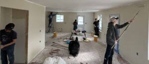 People dispersed in an open room, painting the walls.