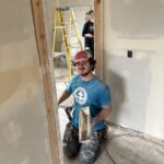 Man kneels in doorway while working on patching home