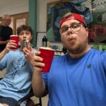 Two people pose for a picutre while holding up red drink cups.