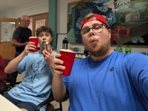Two people pose for a picutre while holding up red drink cups.
