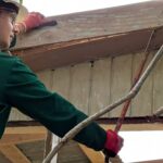 Man working to remove old boards from house.